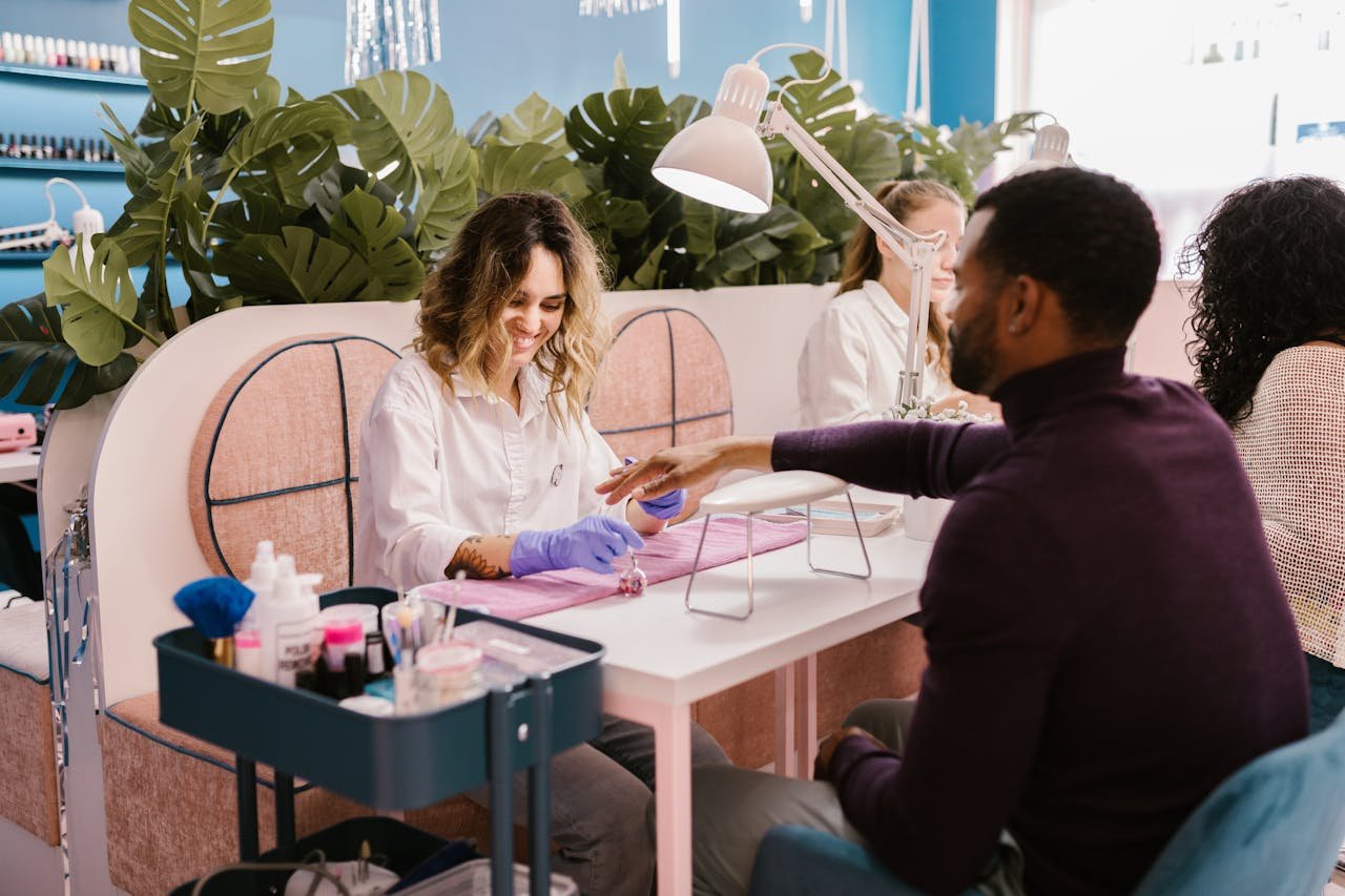 Services A man getting a professional manicure in a stylish, vibrant nail salon setting.